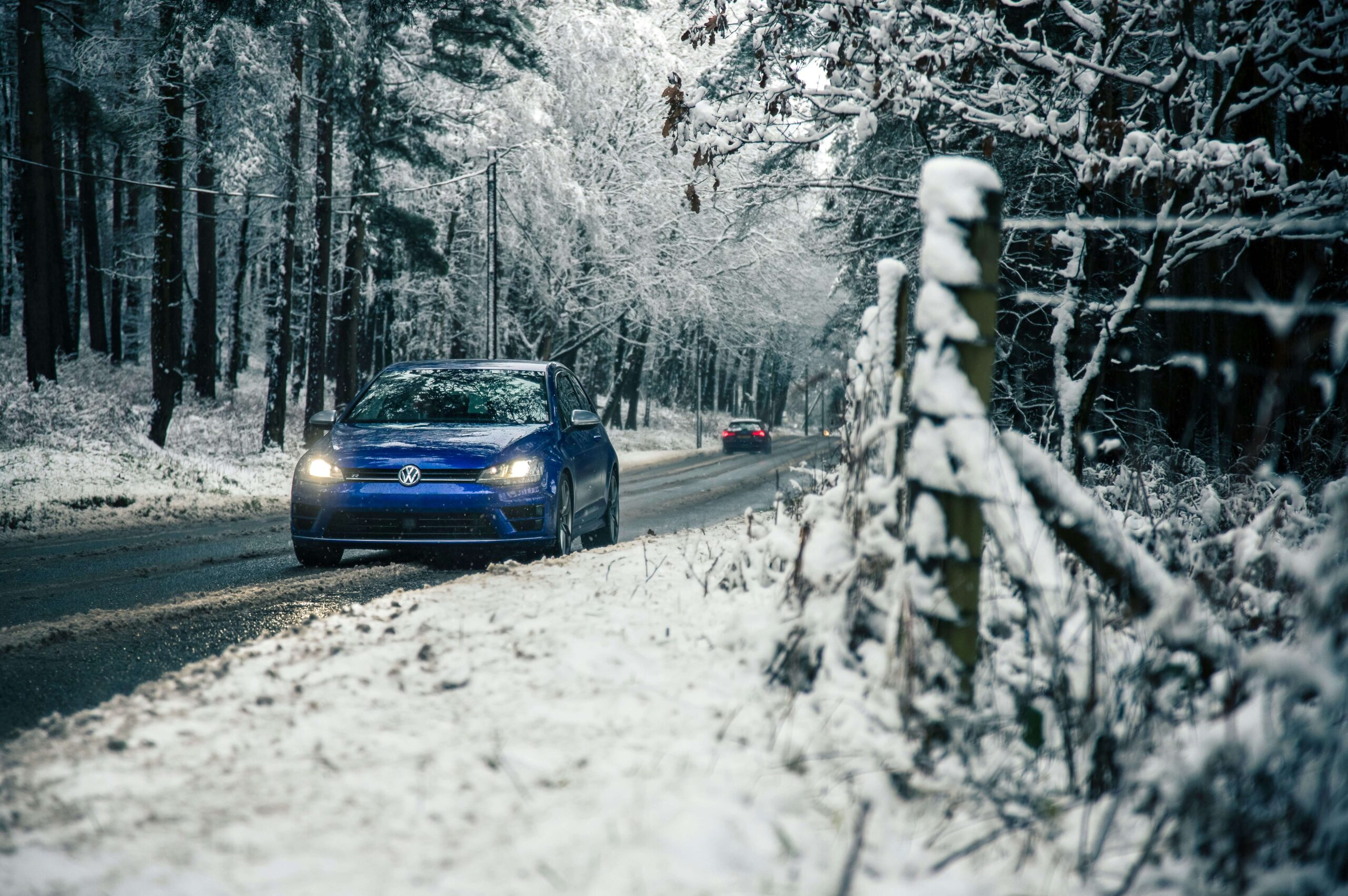 Vinterväglag i skog, två bilar i bild.